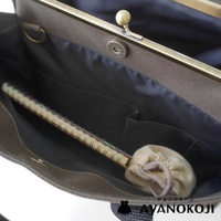 AYANOKOJI 品牌的中型口金托特包內部，可見金色捲式筆記本和一個束口小布袋。