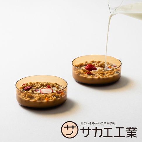 SAKAE 品牌 LOGO，以及兩個裝有麥片和水果的橘色玻璃碗，其中一個碗正被倒入牛奶