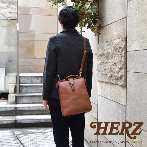 職人手作皮革軟式杜勒斯包，棕色皮革，附有可調式肩帶和頂部提把，包身有金屬釦和皮帶固定。