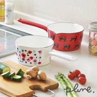 兩個琺瑯單柄牛奶鍋，一個為紅色，印有黑色小貓圖案，另一個為白色，印有多彩花朵圖案。