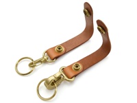 兩件棕褐色皮革鉤扣鑰匙圈，配有黃銅色金屬環和鉤扣，皮革帶上有黃銅色按扣。