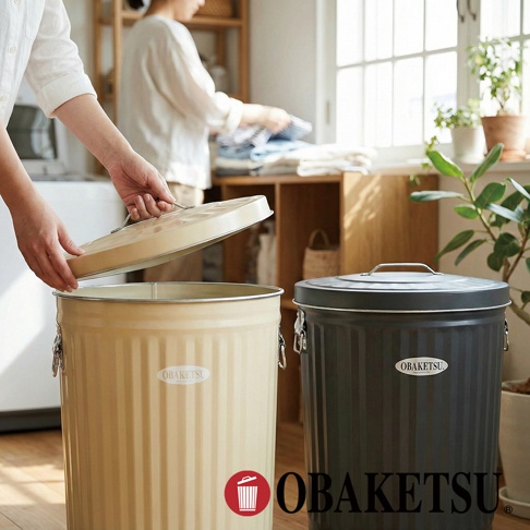 OBAKETSU 品牌黑色與米黃色附蓋金屬垃圾桶，其中米黃色垃圾桶的蓋子正被打開。