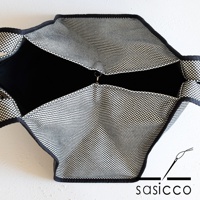 展開狀態的三河木綿刺子織托特包，外層為黑白格紋布料，內裡為黑色，包身邊緣有黑色滾邊，中間有一個金屬扣環。