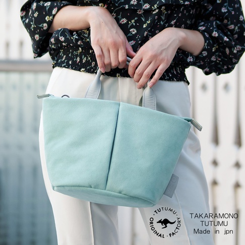 手提薄荷綠麂皮小包，包上有TUTUMU的圓形標誌與TAKARA MONO TUTUMU Made in jpn文字