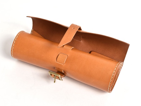 職人手作皮革捲捲收納筆袋，採用天然棕色皮革製成，帶有金屬扣環和縫線細節，可捲起收納筆或小物。