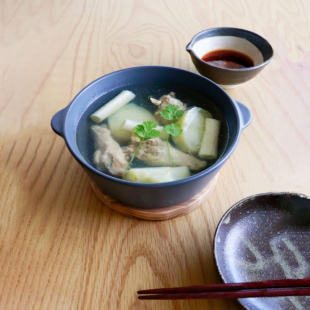 深灰色陶製圓鍋盛有湯品，鍋內有雞肉塊、冬瓜塊和香菜，旁邊配有一小碟醬料和一雙筷子。