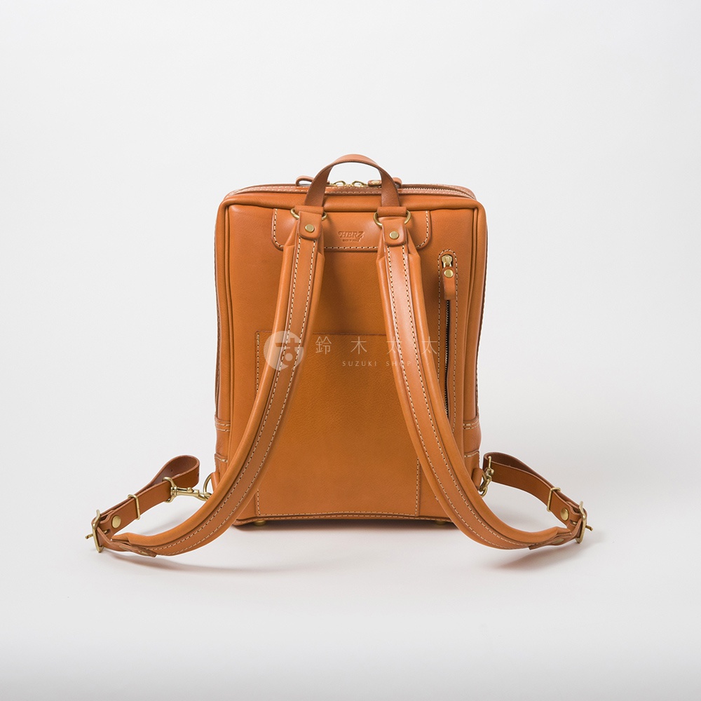棕色皮革後背包，帶有兩個可調節的肩帶，頂部有提把，側面有拉鍊，整體設計簡潔。