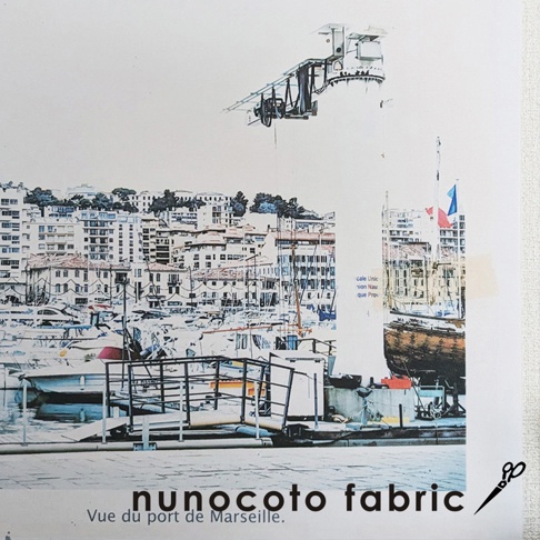 無框帆布藝術海報，描繪馬賽港口景觀。畫面中有眾多船隻停泊，背景是層疊的白色建築，上方有飛機造型的裝置藝術。色彩以藍、白、灰為主，帶有水彩畫風格。
