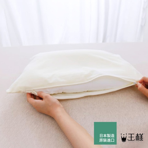 一隻手正在拉開米白色枕頭的拉鍊，露出內部的白色枕芯。