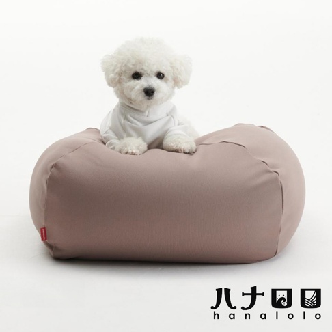 一隻穿著白色上衣的白色比熊犬，正舒適地趴在一個淺咖啡色的長方形柔軟懶骨頭沙發上，背景為簡潔的白色，右下方印有黑色的 hanalolo 品牌標誌。