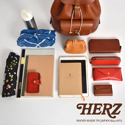 棕色皮革後背包、藍色圓點印花布包、保溫瓶、橘色與紅色皮革小包、長夾、筆袋、紅褐色小錢包、平板電腦、筆記本，以及黑色圓點雨傘。