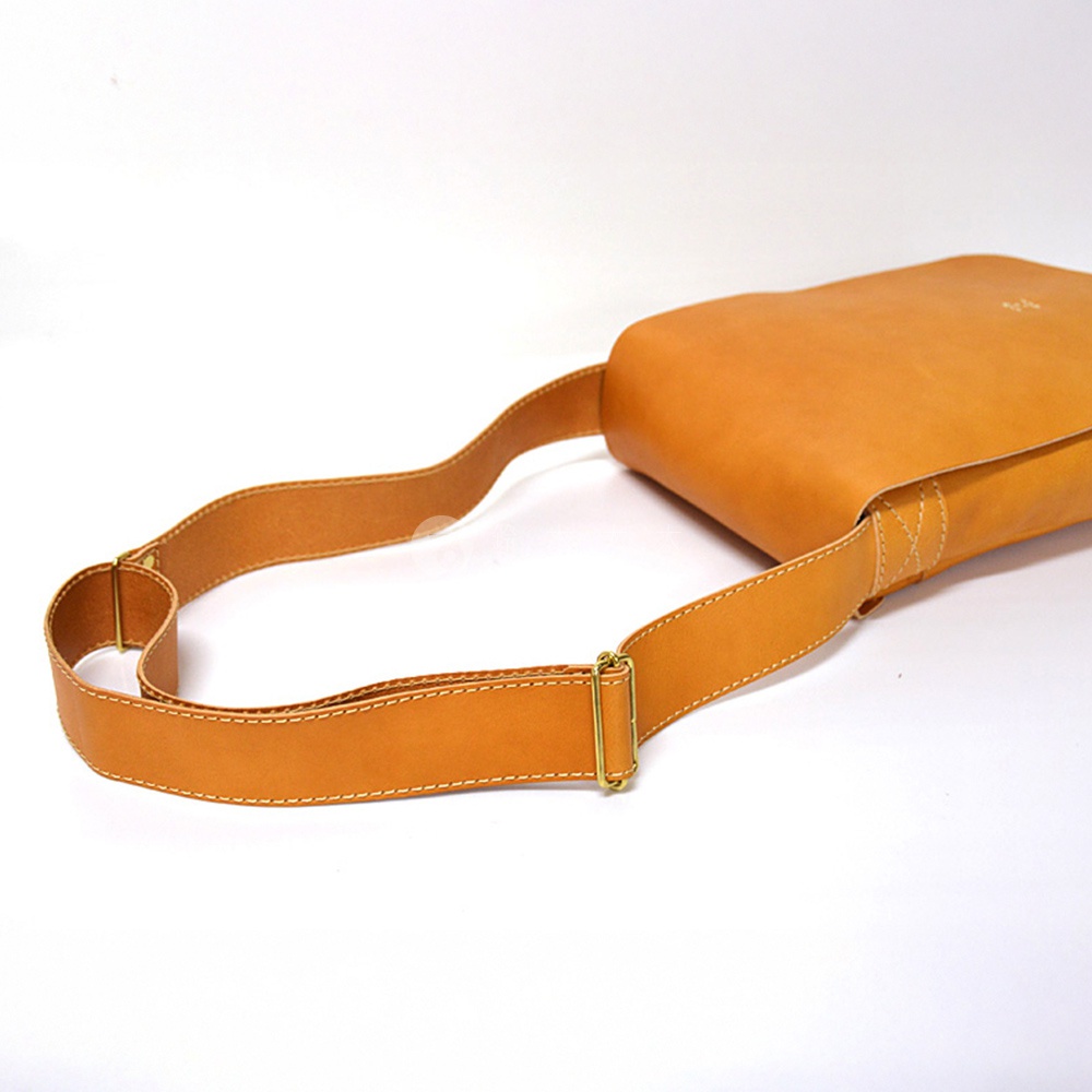 HERZ 日本職人手作皮革軟皮直式斜背包 CK-98，特寫焦糖色皮革斜背包的肩帶與金屬扣環，細膩縫線展現職人手工質感。