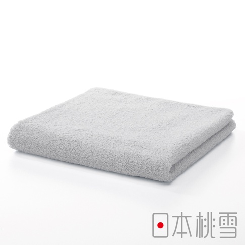 一張淺灰色、柔軟蓬鬆的精梳棉飯店毛巾，對折平鋪於白色背景上，毛巾表面紋理清晰可見。