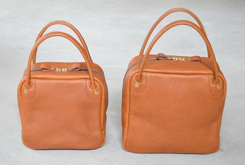 兩個棕色皮革方形托特包，一個較小，一個較大，均有金色拉鍊和提把。