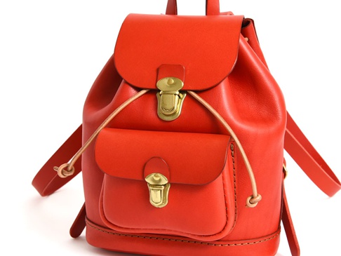 亮紅色皮革迷你後背包，有兩個前袋，皆配有金色搭扣，束繩開口，搭配同色系皮革肩帶。