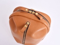 職人手作皮革立體運動斜背包 (F-9)，呈現淺棕色皮革，搭配金色拉鍊與鉚釘，側面有雙拉鍊設計，整體風格簡約，質感厚實。