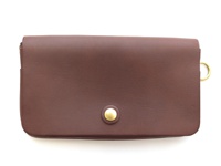 深棕色皮革製成的長夾，正面有一個黃銅色按扣，右側邊緣有一個黃銅色 D 型環。