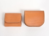 兩個棕褐色皮革零錢包，一個方形，一個帶有圓角蓋子，皆以白色縫線手工製作。