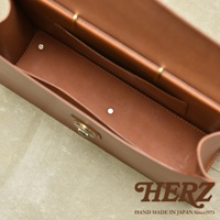 職人手作的駝色皮革Organ兩用商務公事包，包款內部結構清晰，可見多個隔層與金屬旋轉鎖扣，材質光滑細緻。