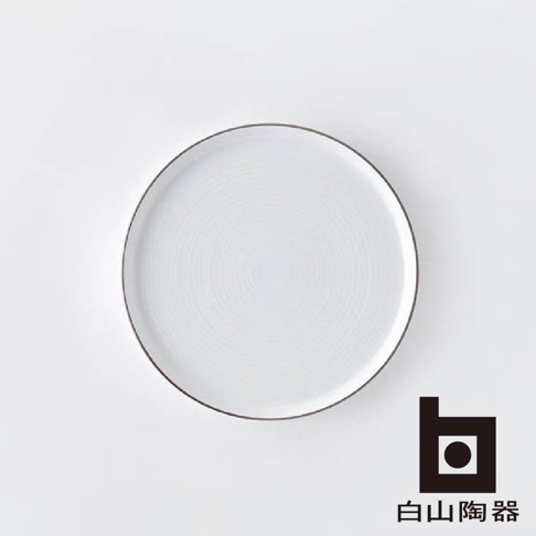 一個白色的圓形陶瓷盤，盤面帶有同心圓紋路，盤緣有一圈細緻的深色邊線。