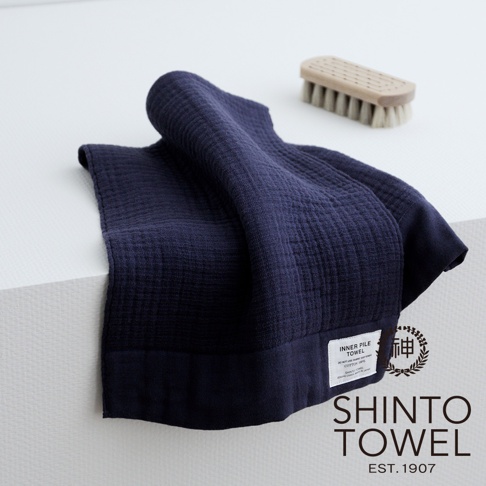 深藍色雙面紗布輕質毛巾，材質為棉，表面有紋理，一角有品牌標籤。