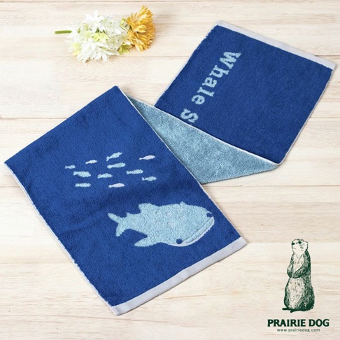 藍色運動毛巾，一面印有淺藍色鯨魚和魚群圖案，另一面印有「Whale S」字樣，觸感柔軟。