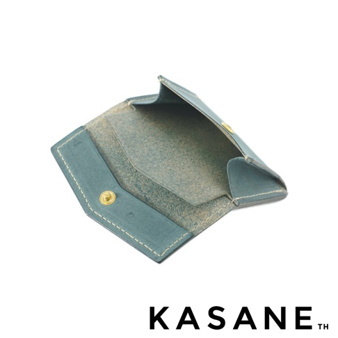 KASANE 品牌標誌旁的藍綠色皮革迷你錢包，細節特寫