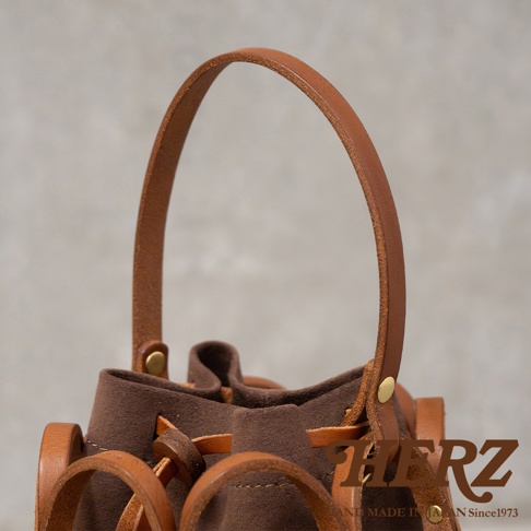 日本HERZ職人手作皮革Organ編織水桶包，駝色皮革提把搭配深棕色包身，簡約提把與抽繩設計