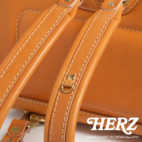 HERZ 品牌手工製作的棕褐色皮革背包，細膩的縫線與金屬配件點綴。