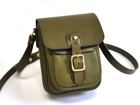橄欖綠皮革製成，直式單肩包，配有皮扣和金色搭扣，有可調節的皮革肩帶。