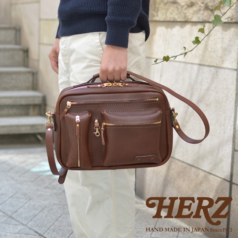 棕色皮革製成的手提斜背包，具有多個拉鍊口袋和可拆卸肩帶。