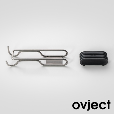 銀色金屬製雙用湯鍋支架，帶有掛勾設計，旁邊為黑色帶有溝槽的矽膠隔熱墊，墊上印有白色品牌標誌。