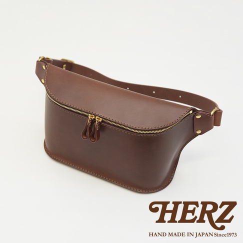 職人手作皮革立體斜背包 F-2，採用深棕色皮革，設有雙拉鍊頭，可調節式皮帶，整體設計簡約。