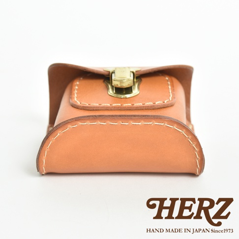 職人手作皮革耳機收納包，採用淺棕色皮革，以白色縫線手工縫製，設有金色金屬釦，風格簡約。