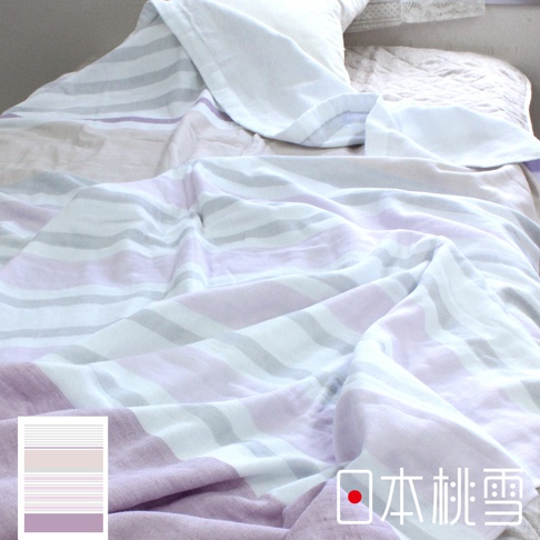 一條淺紫色、粉色與灰色條紋的今治毛巾被，鋪在床上，一角有白色枕頭。
