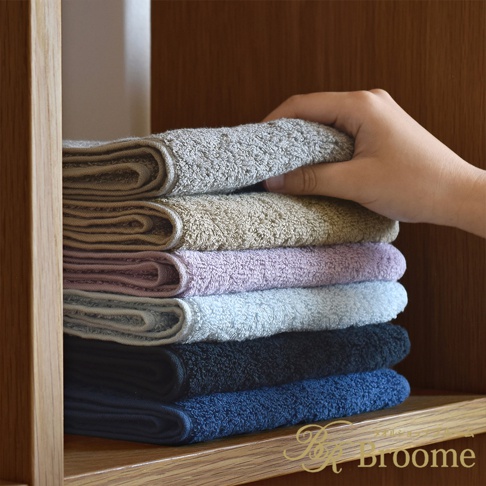 一疊七色長毛巾，顏色由上至下分別為淺灰色、沙色、淡紫色、淺藍色、黑色、深藍色。毛巾材質觸感柔軟，表面有細緻的毛圈。