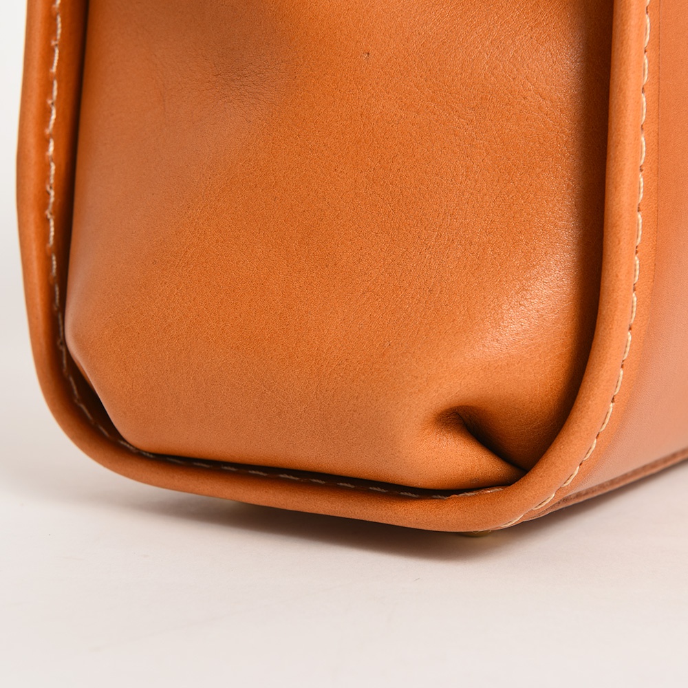 職人手作皮革迷你後背醫生包，棕褐色皮革材質，包角處有精緻縫線，展現細膩工藝。