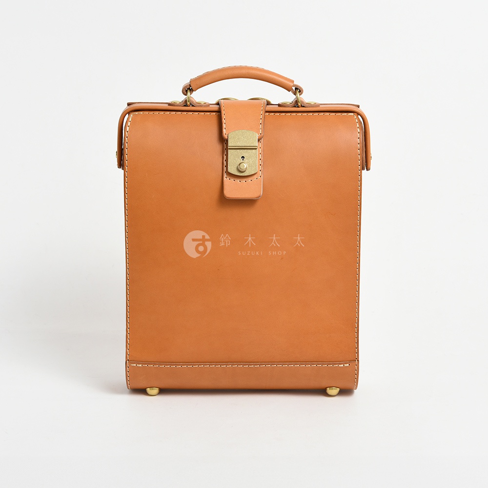 職人手作皮革杜勒斯商務後背包 BJ-10，展示為經典棕褐色，採用真皮材質，配有金色金屬鎖扣、提把及底部防磨腳釘，車縫線整齊。