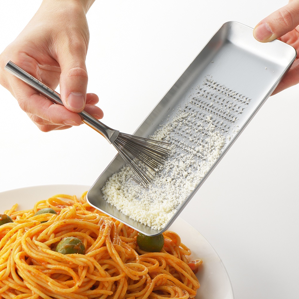 日製料理小刷，不鏽鋼材質，帶有細長的刷毛，用於將細碎的起司從長方形的刨絲器中刮下，灑在盤中的義大利麵上。