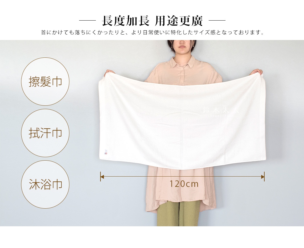 一位女子展示一條白色純棉長浴巾，浴巾有菱形紋理，上面印有日文品牌標誌。浴巾長度約為 120 公分。