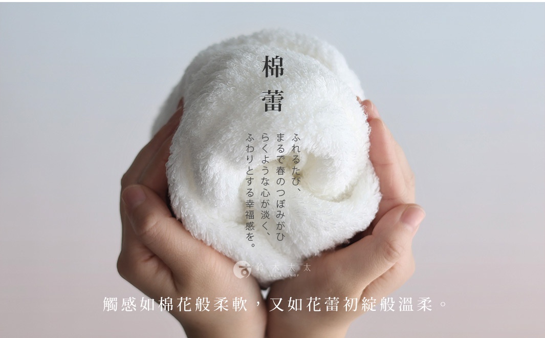 雙手捧著一條蓬鬆柔軟的白色毛巾，上面有日文和中文的詩意文字，描寫其觸感如棉花般柔軟。