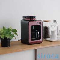 SC-A1210 自動研磨咖啡機，採用黑紅配色，機身線條簡潔。上方為研磨器，下方是玻璃咖啡壺。整體以塑膠和金屬材質為主。