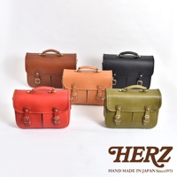 五款職人手作皮革單肩包，包含棕色、淺棕色、黑色、紅色和綠色。包款皆為兩用設計，附有提把與肩帶，並以金屬釦環裝飾。