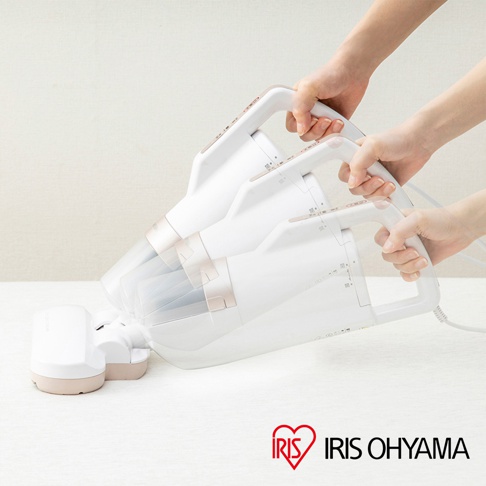 兩隻手正握著白色和玫瑰金色的 IRIS OHYAMA 氣旋偵測除蹣清淨機 IC-FAC3，其透明集塵筒內可見濾網。