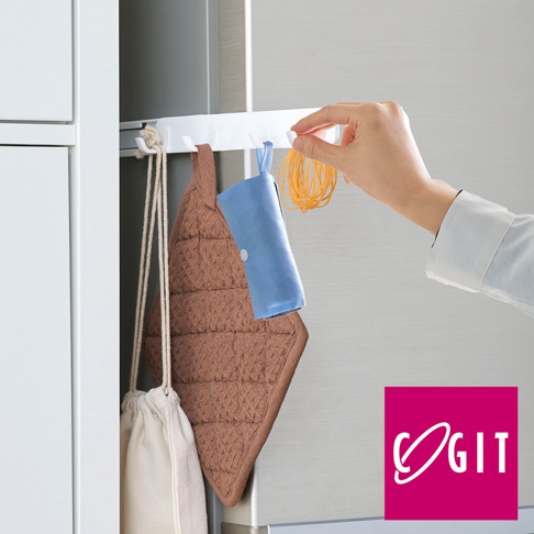 白色磁吸式伸縮掛鉤，附有四個掛勾，懸掛著棕色菱格紋鍋墊、藍色收納袋和一串橘色橡皮筋。