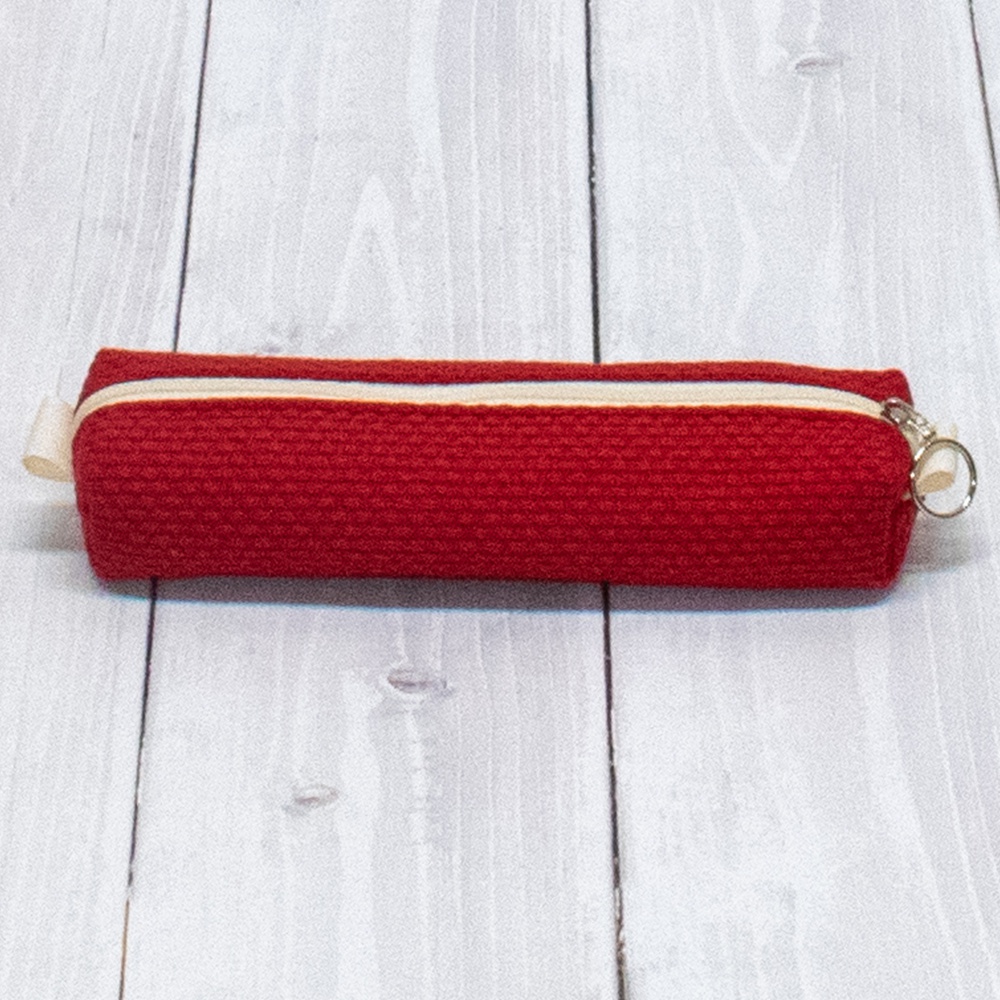紅色三河木綿刺子織筆袋，織紋清晰，搭配米白色拉鍊及同色系拉環，置於淺色木紋背景上。
