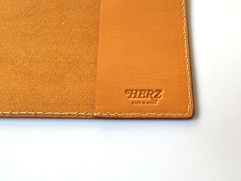 職人手作皮革B5筆記本書套，淺棕色皮革內裡，表面壓印有「HERZ」及「MADE IN JAPAN」字樣，縫線整齊。