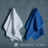 白色與藍色兩條匠心獨技瞬吸乾爽毛巾，材質為柔軟的棉質，毛圈豐厚，質感細膩，邊緣處有精緻的縫線。