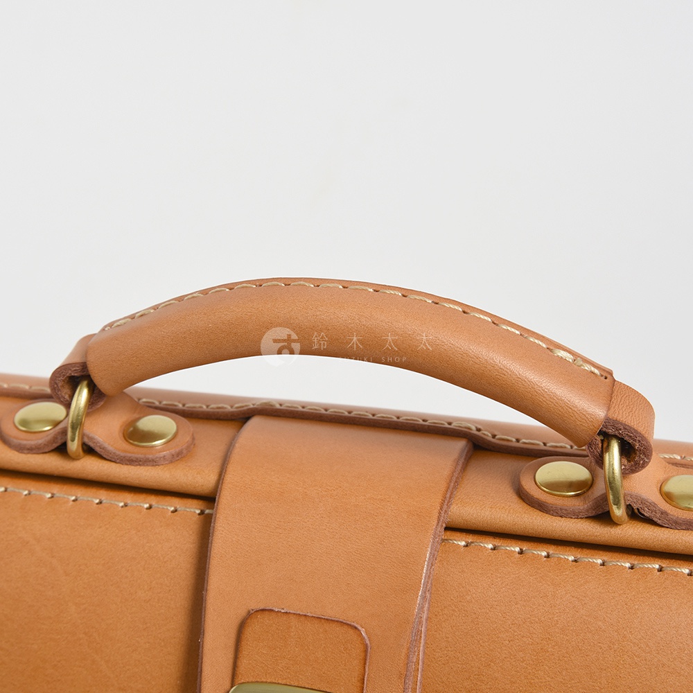 品牌 logo 加上日文文字的特寫，皮革提把和黃銅金屬零件細節