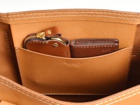 職人手作皮革原子釦托特包內部，深棕色皮革零錢包與卡夾收納於淺棕色皮革隔層內，包體縫線清晰可見。